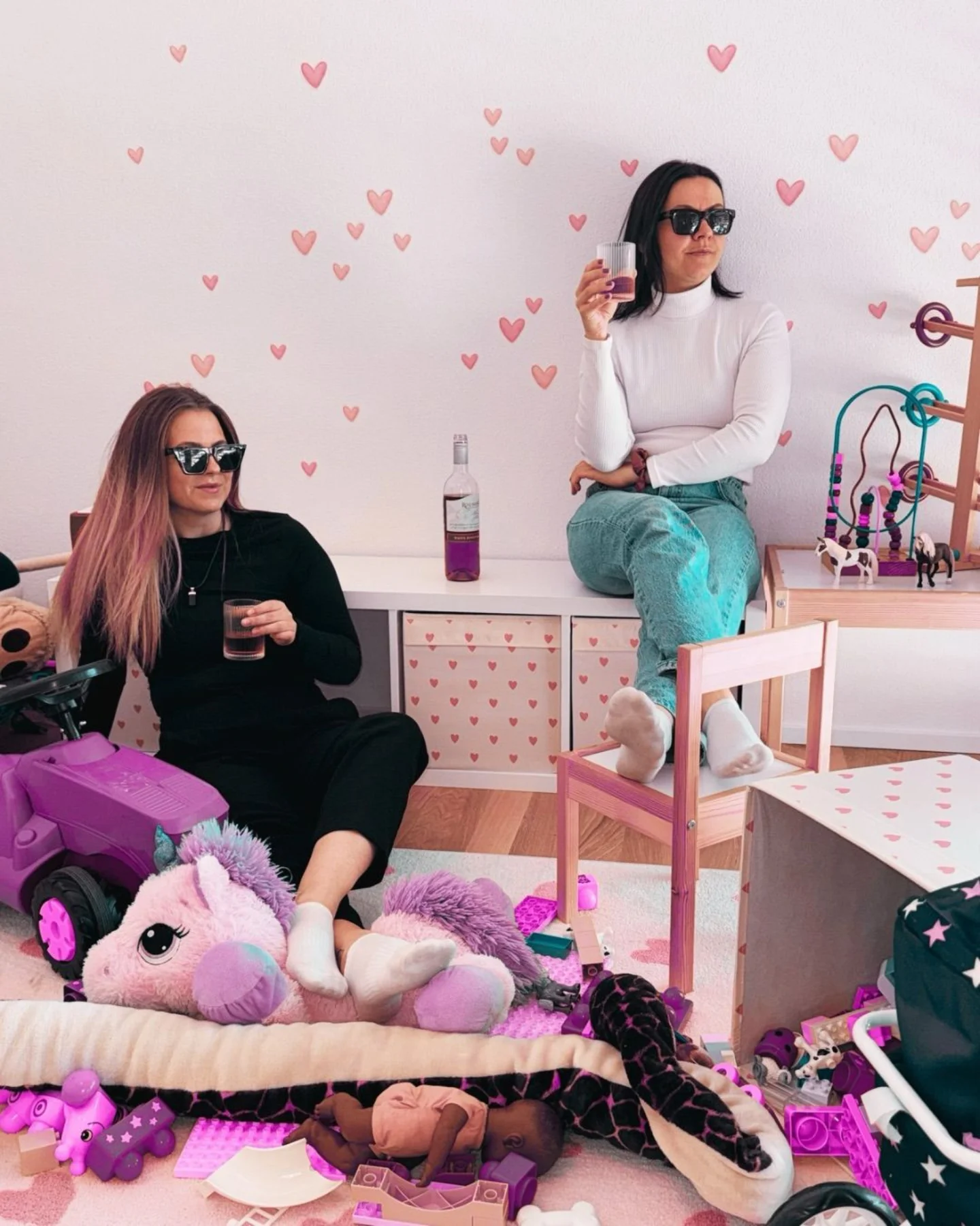 Mary und Milena mit Sonnenbrille und einem Glas Rosé mitten im Kinderzimmerchaos
